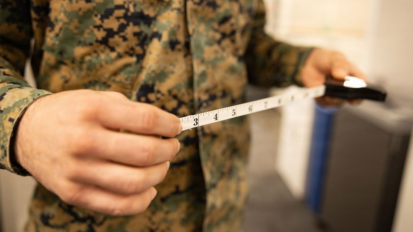 A U.S. Marine with Training and Education Command poses with a retractable measuring tape used for body composition assessment at Marine Corps Base Quantico, Virginia, Feb. 6, 2026. The Marine Corps is replacing the current semiannual height and weight screening with a waist-to-height ratio (WHtR) methodology as the initial step in its body composition evaluation process, in accordance with recent guidance from the Secretary of War. (U.S. Marine Corps photo by SSgt. Claudia Nix)