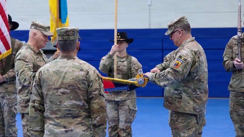 U.S. Army Col. Frank Tantillo, commander of the 86th Infantry Brigade Combat Team (Mountain), Vermont National Guard, and Command Sgt. Maj. Andrew Campagne, command sergeant major of the 86th Infantry Brigade Combat Team (Mountain), unfurl the brigade colors during a Joint Multinational Training Group–Ukraine transfer of authority ceremony at Grafenwoehr Training Area, Germany, Feb. 18, 2026.