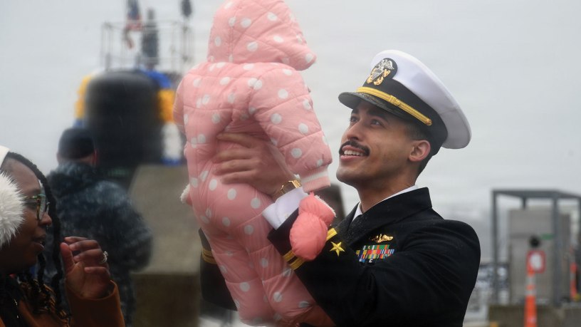Lt. Berl McLaurin, assigned to the Virginia-class nuclear-powered fast-attack submarine USS South Dakota (SSN 790), meets his daughter for the first time as South Dakota returns to Naval Submarine Base New London in Groton, Conn., Feb. 20, 2026, following a six-month deployment to the U.S. European Command area of responsibility. South Dakota and crew operate under Submarine Squadron (SUBRON) 4, whose primary mission is to provide attack submarines that are ready, prepared, and committed to meet the unique challenges of undersea combat and deployed operations in unforgiving environments across the globe. (U.S. Navy photo by Chief Mass Communication Specialist Darren M. Moore)