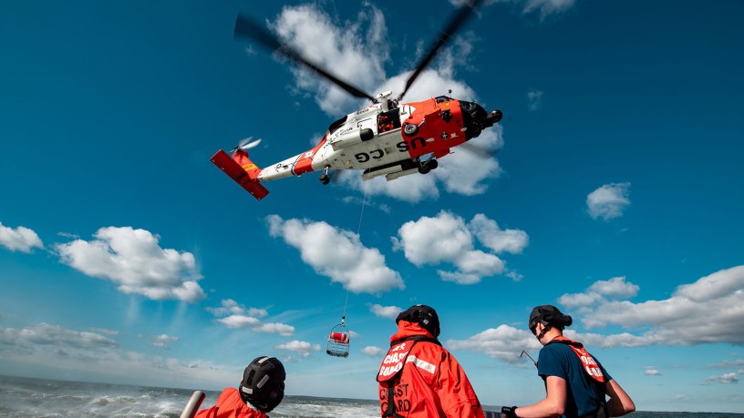 Crew members aboard a U.S. Coast Guard 45-foot Response Boat–Medium from Coast Guard Station Chincoteague look up at an MH-60T Jayhawk helicopter during a training evolution off the coast of Chincoteague, Virginia, Oct. 27, 2025. The training enhances coordination and communication between air and surface assets, ensuring crews are prepared to respond effectively during real-world search and rescue missions. (U.S. Coast Guard photo by Petty Officer 3rd Class Matt Thieme)