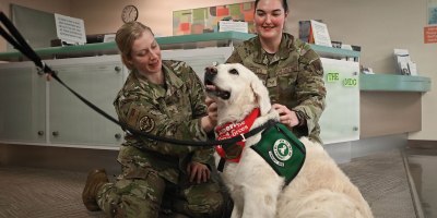 Staff Sgt. Hannah Gerics, 55th Operational Medical Readiness Squadron ophthalmic technician, and Senior Airman Kylie Pacheco, 55th Medical Group medical technician, pet therapy dog, Izy, during her visit to the 55th Medical Group's Ehrling Bergquist clinic in Bellevue, Neb., Jan. 9, 2026. Therapy dogs are tested and evaluated to determine whether they have the personality and demeanor to become therapy dogs. (U.S. Air Force photo by Daniel Martinez)