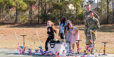 U.S. Space Force 2nd Lt. Dominic Anastasio and 2nd Lt. Athena Gesite, 1st Range Operations Squadron range operations commanders in training, observe as students launch paper rockets in Brevard County, Florida, Feb. 19, 2026. Through hands-on activities like rocket design and launch demonstrations, Guardians helped students explore basic engineering principles while strengthening connections between the Space Force and the local community that supports the Eastern Range mission. (U.S. Space Force photo by Gwen Kurzen)