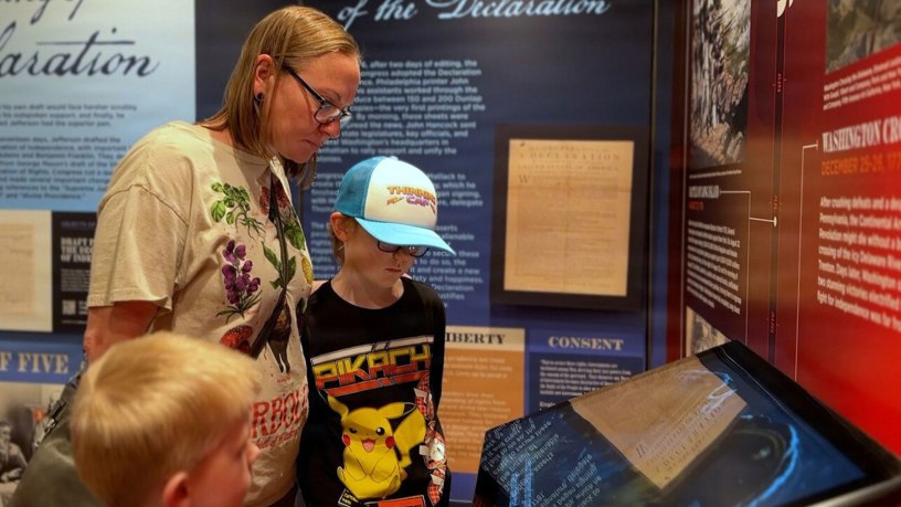 Tracy Warren and her children interact with a high-definition touch screen inside the Freedom 250 mobile museum at Fort Campbell, Ky., Feb. 25, 2026. The Warren family, who recently studied the American Revolution as part of their homeschool curriculum, used the exhibit's interactive technology to further explore 250 years of United States history.