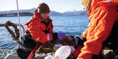 U.S. Navy Lt. Hannah Cunningham, left, assigned to En-route Care System (ERCS) Team 52, and U.S. Navy Hospital Corpsman 1st Class Daniel Rodriguez, right, assigned to ERCS Team 52, treat a patient aboard a small boat during a ship-to-shore medical evacuation exercise as part of ARCTIC EDGE 2026 (AE26) in Kodiak, Alaska, Feb. 26, 2026. AE26 is a NORAD and U.S. Northern Command-led homeland defense exercise designed to improve readiness, demonstrate capabilities, and enhance Joint and Allied Force interoperability in the Arctic. (U.S. Navy photo by Mass Communication Specialist 1st Class Abigayle Lutz)