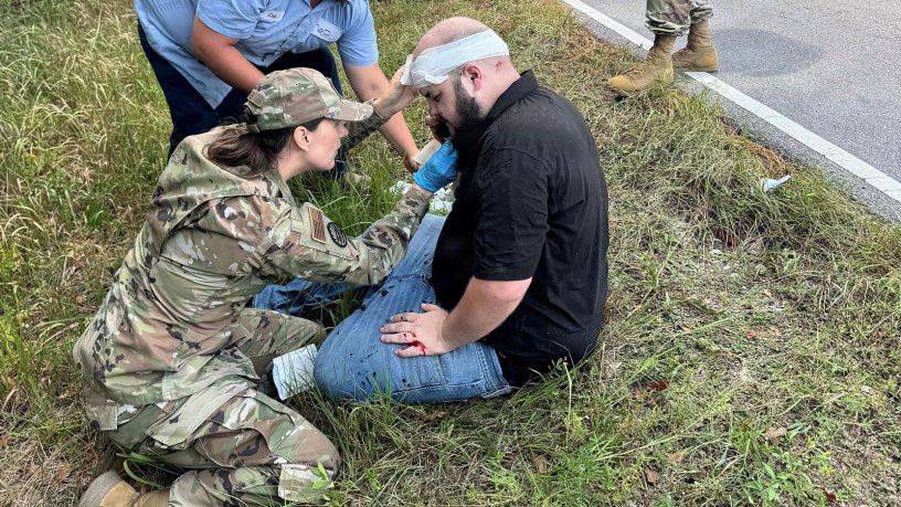 Montana Air Guard Capt. Caitlyn Cayer, who is also a nurse practitioner, administers aid to a man involved in a traffic wreck in Gulfport, Miss., Sept. 22, 2025. Master Sgt. Kraig Kimball, top right, helped pull the driver from a car fire and escorted him to safety seconds before the car engulfed in flames.