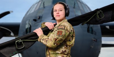 Senior Airman Kaylee Hess, an aeromedical evacuation technician with the 187th Aeromedical Evacuation Squadron, 153rd Airlift Wing, Wyoming Air National Guard, stands in front of a C-130 Hercules aircraft assigned to the 153rd Airlift Wing while holding a folded litter in Cheyenne, Wyo., March 5, 2026. Hess was named the 2025 Outstanding Aeromedical Evacuation Crew Member of the Year. (U.S. Air National Guard photo by Master Sgt. Jon Alderman)