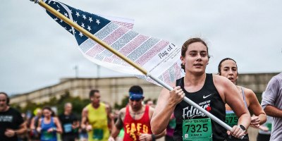 U.S. Air Force Capt. Hanna Born, 23rd Flying Training Squadron instructor pilot, carries the "Flag of Honor" during the 2025 Army Ten-Miler in Washington, D.C., Oct. 12, 2025. The flag is inscribed with the names of all 2,977 victims of the Sept. 11, 2001, terrorist attacks. The race is part of Born’s "Run to Remember 2,977" mission, a personal commitment to run 2,977 miles, one mile for every life lost, to ensure the next generation continues to honor our nation’s promise to Never Forget. (courtesy photo)