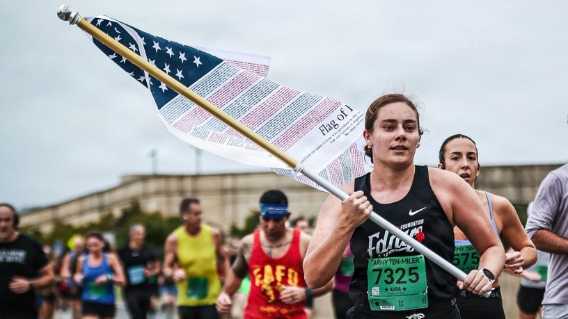 U.S. Air Force Capt. Hanna Born, 23rd Flying Training Squadron instructor pilot, carries the "Flag of Honor" during the 2025 Army Ten-Miler in Washington, D.C., Oct. 12, 2025. The flag is inscribed with the names of all 2,977 victims of the Sept. 11, 2001, terrorist attacks. The race is part of Born’s "Run to Remember 2,977" mission, a personal commitment to run 2,977 miles, one mile for every life lost, to ensure the next generation continues to honor our nation’s promise to Never Forget. (courtesy photo)