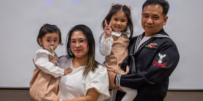 Electrician's Mate Second Class, Jay ar Fernandez, poses for a photo with his family after receiving a naturalization certificate during a United States Citizenship and Immigration Services naturalization ceremony hosted by Region Legal Service Office Western Pacific, at CFAY’s Community Readiness Center.