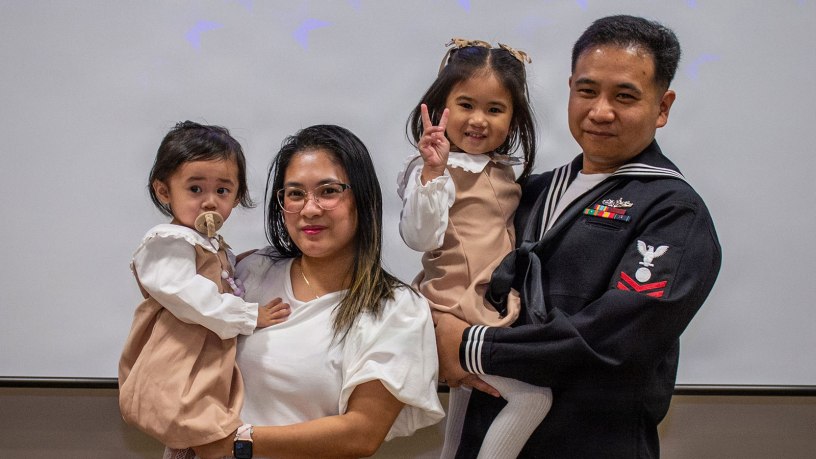 Electrician's Mate Second Class, Jay ar Fernandez, poses for a photo with his family after receiving a naturalization certificate during a United States Citizenship and Immigration Services naturalization ceremony hosted by Region Legal Service Office Western Pacific, at CFAY’s Community Readiness Center.