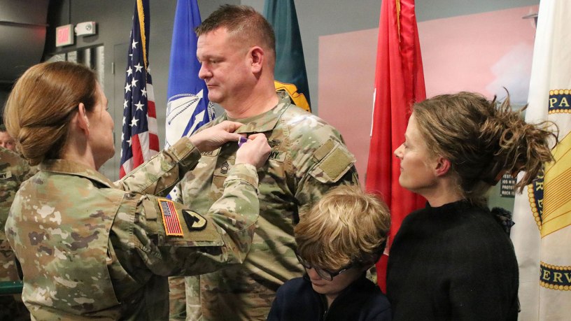 Maj. Gen. Stephanie Howard, director, Defense Logistics Agency Joint Reserve Force, pins the Purple Heart Medal on Master Sgt. Anthony Patera, contracting officer, during a ceremony held March 13 at the Rock Island Arsenal Museum, Illinois.