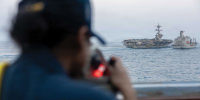 A U.S. Sailor, assigned to Arleigh Burke-class guided-missile destroyer USS Spruance (DDG 111), looks out as Nimitz-class aircraft carrier USS Abraham Lincoln (CVN 72) conducts a replenishment-at-sea with fleet replenishment oiler USNS Henry J. Kaiser (T-AO-187) during Operation Epic Fury, March 18, 2026. (U.S. Navy photo)