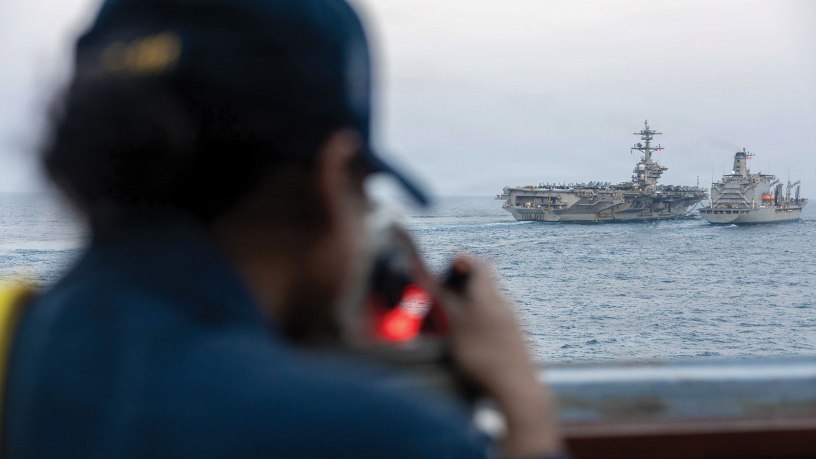 A U.S. Sailor, assigned to Arleigh Burke-class guided-missile destroyer USS Spruance (DDG 111), looks out as Nimitz-class aircraft carrier USS Abraham Lincoln (CVN 72) conducts a replenishment-at-sea with fleet replenishment oiler USNS Henry J. Kaiser (T-AO-187) during Operation Epic Fury, March 18, 2026. (U.S. Navy photo)