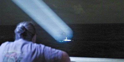 U.S. Coast Guard Lt. Cmdr. Stephanie Jocis, operations officer aboard Legend-class cutter USCGC Midgett (WMSL 757), observes a 23-foot single-outboard skiff vessel, carrying three members of a missing family in the waters of Chuuk State, Federated States of Micronesia, in Midgett’s search light during the early hours of April 6, 2026. The crew of Midgett rescued the family after the vessel went missing on March 30 in the waters of Chuuk State. U.S. Coast Guard missions in the Indo-Pacific focus on issues directly supporting and advancing our regional partners’ efforts to protect fish stocks and ensure the safety of life at sea, ensuring a secure and prosperous Indo-Pacific. (U.S. Coast Guard photo by Seaman Lauren Taber)