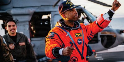 NASA astronaut Victor Glover points at crew members on the flight deck of the San Antonio Class amphibious transport dock USS John P. Murtha (LPD 26) after returning from space on Apr. 10, 2026. John P. Murtha is underway in the U.S. 3rd Fleet area of operations supporting NASA’s Artemis II mission, retrieving the crew and spacecraft following their return to Earth and splashdown in the Pacific Ocean. NASA’s Artemis II mission sent four astronauts on a flight around the moon in the Orion space craft, marking the first time humans journeyed to deep space in over 50 years. (U.S. Navy photo by Mass Communication Specialist 2nd Class August Clawson)