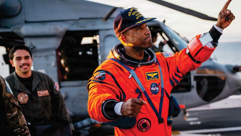 NASA astronaut Victor Glover points at crew members on the flight deck of the San Antonio Class amphibious transport dock USS John P. Murtha (LPD 26) after returning from space on Apr. 10, 2026. John P. Murtha is underway in the U.S. 3rd Fleet area of operations supporting NASA’s Artemis II mission, retrieving the crew and spacecraft following their return to Earth and splashdown in the Pacific Ocean. NASA’s Artemis II mission sent four astronauts on a flight around the moon in the Orion space craft, marking the first time humans journeyed to deep space in over 50 years. (U.S. Navy photo by Mass Communication Specialist 2nd Class August Clawson)