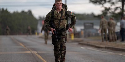 An Irish Defence Forces soldier crosses the finish line of the 12-mile ruck during the 2026 Massachusetts National Guard Best Warrior Competition at Camp Edwards, Massachusetts, April 17, 2026. The three-day competition brought together more than 40 soldiers, noncommissioned officers and airmen from the Massachusetts National Guard and Irish Defence Forces, testing them physically and mentally while enhancing skills, building relationships and expanding professional knowledge. (Air National Guard photo by Senior Airman Julia Ahaesy)