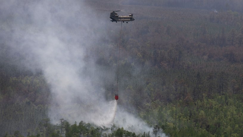 A CH-47 Chinook helicopter crew with Bravo Company, 1st General Support Aviation Battalion, 169th Aviation Regiment, 78th Aviation Troop Command, Georgia Army National Guard, dumps water with a Bambi Bucket during the wildfire suppression efforts in Pineland, Georgia, April 25, 2026. Defense plays an integral role in declared emergencies by providing a versatile and ready force capable of responding to natural and manmade disasters across the United States. (U.S. Army National Guard photo by Sgt. Jordan McNeal)