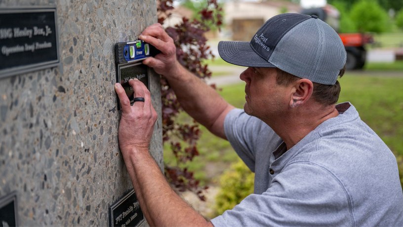Arkansas Dept. of the Military employee Kevin Shaffer installs a plaque April 29, 2026, that honors Pfc. James Reginato who was injured by enemy fire in Mignano, Italy, on Dec. 15, 1943. He succumbed to his injuries two days later on Dec. 17, 1943. Col. Matt Anderson spent two years conducting research on his own time, finding six Soldiers to add to the memorial.