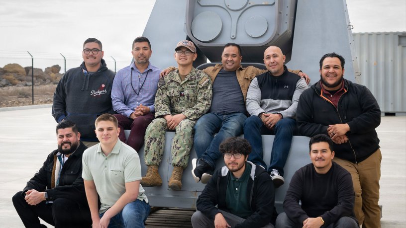 Directed energy team members with Naval Surface Warfare Center, Port Hueneme Division gather around the Optical Dazzling Interdictor, Navy (ODIN) behind the Directed Energy Systems Integration Laboratory (DESIL) onboard Naval Base Ventura County Point Mugu in California on Jan. 30, 2025. DESIL now offers courses on operating and maintaining ODIN, giving sailors and other students hands-on experience with the directed energy system in a training environment. (U.S. Navy photo by Eric Parsons)