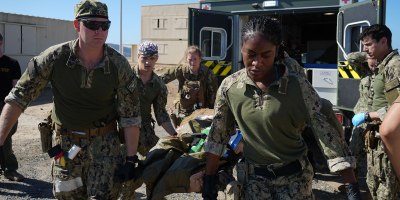 Hospital Corpsman 2nd Class Nya Jobs (right), respiratory therapist, Lt. j.g. Mark Gregg (left), trauma nurse, Capt. David Samaha (middle), general surgeon, and Lt. j.g. Melissa Sullivant (back), trauma nurse, all assigned to Navy Medicine Readiness and Training Command (NMRTC) Jacksonville, transport a casualty from an ambulance into their mission support site during an Expeditionary Resuscitative Surgical System (ERSS) course conducted by Naval Expeditionary Medicine Warfighter Development Center (NEMWDC) Oct. 21, 2025.