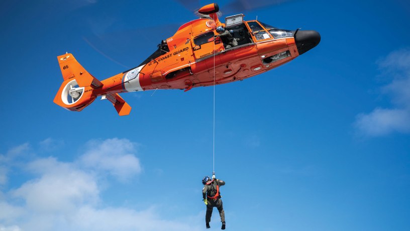 U.S. Coast Guard Petty Officer 2nd Class Kimble Petersen, an aviation survival technician assigned to Coast Guard Air Station Barbers Point in Kapolei, Hawaii, is lowered from a Coast Guard MH-65 Dolphin helicopter during a training exercise in Kaneohe Bay, Hawaii Nov. 12, 2025. Coast Guard rescue swimmers train to operate in high seas, heavy surf, and extreme weather conditions, ensuring they can respond during hurricanes, storms, and ship disasters. (U.S. Coast Guard photo by Petty Officer 2nd Class Tyler Robertson)