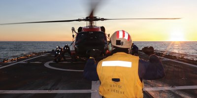 U.S. Coast Guard Ensign Garth Bowman, a landing signal officer assigned to U.S. Coast Guard Cutter Waesche (WMSL 751), directs an MH-60 Jayhawk helicopter from Air Station Kodiak during flight operations in the Bering Sea, Feb. 21, 2026. Training is essential to maintaining unit readiness and proficiency for Waesche and the air stations. (U.S. Coast Guard photo by Petty Officer 3rd Class Christian Swenk)