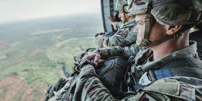 Staff Sgt. Taylor Siebrandt and Sgt. 1st Class James Miller, with Team 6 representing the Army National Guard Warrior Training Brigade, sit in the open door of a UH-60 Black Hawk helicopter in flight to prepare for their spot jump onto Fryar Drop Zone during the 2026 Best Jumpmaster Competition at Fort Benning, Georgia, April 8, 2026. The competition tested the proficiency and precision of jumpmaster teams through a series of tactical airborne operations. (U.S. Army photo by Capt. Stephanie Snyder)
