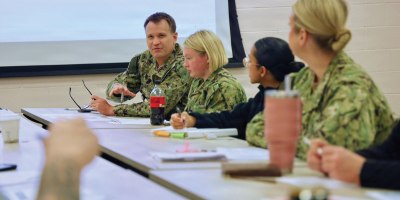 Capt. Mark Miller (back left), chief nursing officer assigned to Navy Medicine Readiness and Training Command Twentynine Palms, discusses the impact a hypothetical pandemic would have on the command with hospital leadership during an influenza pandemic tabletop exercise April 9, 2026.