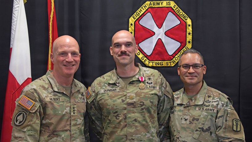 Major Michael Dunbar, 65th Medical Brigade (center), poses for a photo after being awarded the Army Meritorious Service Medal by Lt. Gen. Joe Hilbert, Eighth Army commanding general (left), for winning first place at the Fiscal Year 26 Pacific Victors Innovation Challenge. Far right is Col. Edgar Arroyo, 65th Medical Brigade commander.