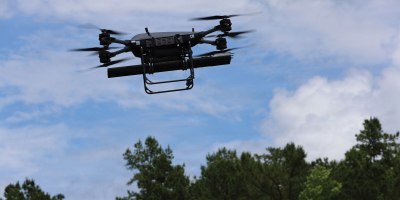 A TRV-150 resupply drone undergoes flight testing at Fort Rucker, Ala., to evaluate flight control software and physical response while carrying a 70 mm rocket launcher. The industry-led initiative aims to provide expeditionary units with organic, precision-strike options using existing inventory like the Hydra family of rockets.