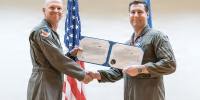 Col. Christipher Hubbard, acting 388th Fighter Wing commander presents the Distinguished Flying Cross to Maj. Alexander Cox during a ceremony at Hill Air Force Base, Utah, May 21, 2026. Cox also received a Bronze Star. Both decorations were awarded for actions during a 2025 deployment to the United States Central Command area of responsibility, including participation in Operation Midnight Hammer. (U.S. Air Force photo by Cynthia Griggs)