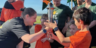 Joint Base Lewis-McChord Provost Marshal Lt. Col. Abby Lanni helps Special Olympics Washington athletes hold the Flame of Hope before starting the 2026 Law Enforcement Torch Run for Special Olympics Washington on May 21 near the Iron Mike statue on JBLM, Lewis Main.