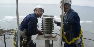 Petty Officer 3rd Class Jason Flores and Petty Officer 1st Class Juan Diaz, members of U.S. Coast Guard Aids to Navigation Team San Diego, verify that the newly installed light-emitting diode beacon is level atop the Point Loma lighthouse in San Diego, Feb. 6, 2013.