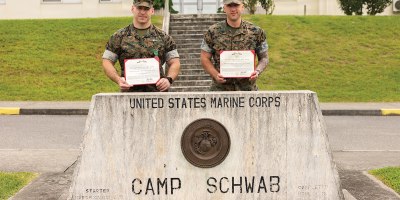 U.S. Marine Corps Staff Sgt. Zachary Robbin, right, an infantry platoon sergeant, and Navy Hospital Corpsman 1st Class Thomas Musumeci, a leading petty officer, both with 1st Battalion, 25th Marines, forward deployed to 4th Marine Regiment, 3rd Marine Division as part of the unit deployment program, pose for a photo with their Navy and Marine Corps Achievement Medals on Camp Schwab, May 14, 2026.