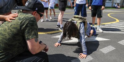 U.S. Army Reserve Staff Sgt. Joseph Callaway, signal support sergeant with the 418th Civil Affairs Battalion, 308th Civil Affairs Brigade, 353rd Civil Affairs Command, watches as the child is doing pushups with military apparel from the Primary school on June 01, 2026, in Poznan, Poland.