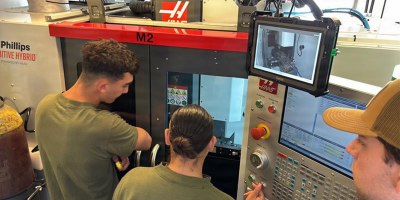 Marines assigned to 1st Maintenance Battalion observe a machining operation on the Advanced Integrated Mobile Machine Shop (AIMMS) hybrid system alongside Naval Surface Warfare Center, Carderock Division engineer Ryan Fisher during new equipment training (NET) on May 4, 2026.