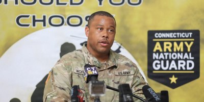 U.S. Army Sgt. Sinclair Worrell Oliver, a soldier assigned to the 130th Public Affairs Detachment, introduces Maj. Michael Wilcoxson, the Connecticut National Guard's state public affairs officer roleplaying as the state's adjutant general, during a mock press conference during Yankee Thunder, a crisis communication exercise at the Gov. William A. O'Neill Armory in Hartford, Conn. June 11, 2026.