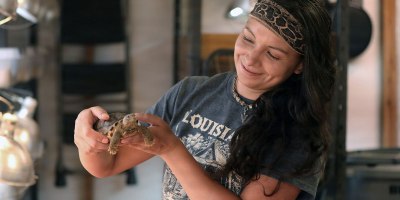 Amy Moseley, a biological science field technician with The Nature Conservancy, inspects a young gopher tortoise during Operation Sentinel Justice at Camp Shelby, Mississippi, June 15. 2026.