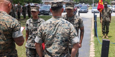 U.S. Marine Corps Cpl. Emily Martinez, left, a transmissions system operator, and Cpl. Johnny Tamayo, a ground electronics transmission systems maintainer, both with 3rd Battalion, 6th Marine Regiment, 2nd Marine Division, stand at attention during an award ceremony on Marine Corps Base Camp Lejeune, June 25, 2026.