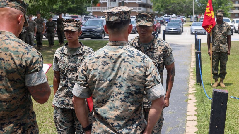 U.S. Marine Corps Cpl. Emily Martinez, left, a transmissions system operator, and Cpl. Johnny Tamayo, a ground electronics transmission systems maintainer, both with 3rd Battalion, 6th Marine Regiment, 2nd Marine Division, stand at attention during an award ceremony on Marine Corps Base Camp Lejeune, June 25, 2026.