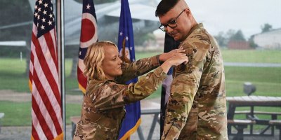 U.S. Air Force Lt. Col. Britney Hensley, commander of the 126th Intelligence Squadron, removes the 126th IS unit patch from Tech. Sgt. Dylan Jacques, an intelligence analyst assigned to the 126th IS at Springfield-Beckley Air National Guard Base, who transferred to the 76th Intelligence, Surveillance and Reconnaissance Squadron in a historic ceremony June 26, 2026.
