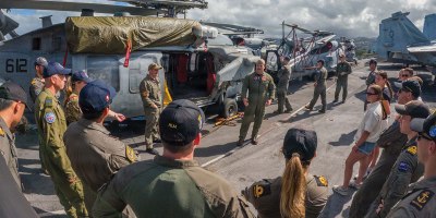 U.S. Navy Lt. Dom Castelli, assigned to Helicopter Sea Combat Squadron (HSC) 8, speaks to sailors from partner countries during an international helicopter experience exchange event on the flight deck of the Nimitz-class aircraft carrier USS Theodore Roosevelt during Exercise Rim of the Pacific 2026.
