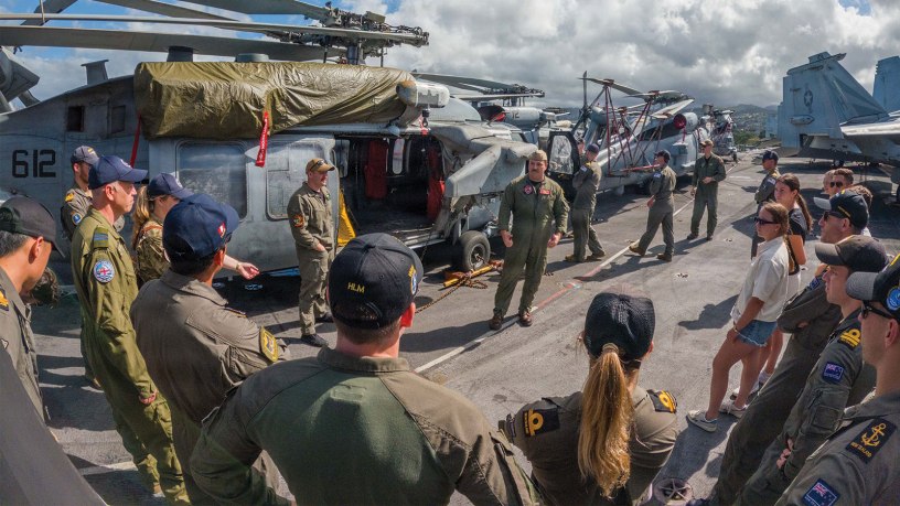 U.S. Navy Lt. Dom Castelli, assigned to Helicopter Sea Combat Squadron (HSC) 8, speaks to sailors from partner countries during an international helicopter experience exchange event on the flight deck of the Nimitz-class aircraft carrier USS Theodore Roosevelt during Exercise Rim of the Pacific 2026.