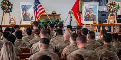 A memorial display featuring battlefield crosses, portraits, personal effects and wreaths honoring U.S. Army 1st Lt. Kendrick Key and U.S. Army Spc. Mariyah Collington, who served with 5th Battalion, 4th Air Defense Artillery Regiment, 52D Air Defense Artillery Brigade, 10th Army Air & Missile Defense Command, stands inside Katterbach Chapel as soldiers and attendees gather for a memorial ceremony at Katterbach Kaserne, Germany, June 29, 2026.