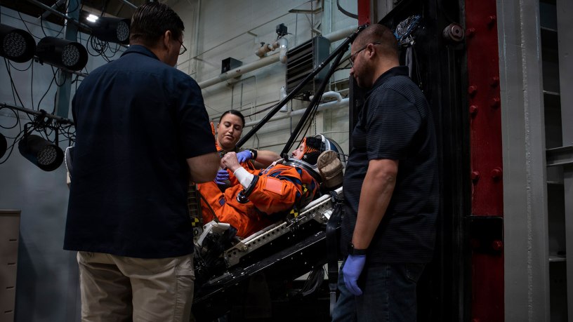 An Air Force Research Laboratory team and NASA prepare a U.S. Air Force volunteer in the vertical deceleration tower at Wright-Patterson Air Force Base, Ohio, Nov. 3, 2023, to test the next replica of a space suit and seat for the Orion spacecraft.