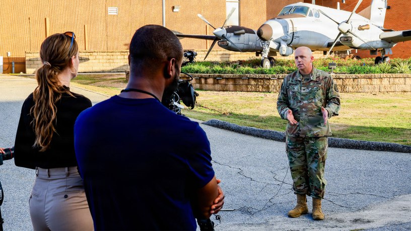 116th Military Intelligence Brigade Commander Col. Matthew McGraw discusses the history of the brigade and evolution of Army Aerial Intelligence, Surveillance, and Reconnaissance (AISR) in front of the RC-12K Guardrail aircraft at Ft. Gordon, Georgia., on November 15, 2024.
