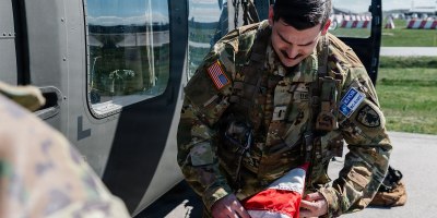 Colorado Army National Guard 1st Lt. Kellen Jansen, assistant operations officer with Headquarters and Headquarters Company, 2nd Battalion, 135th Aviation Regiment (General Support Aviation Battalion), assigned to Kosovo Force (KFOR) Regional Command-East, folds a U.S. flag at Camp Bondsteel, Kosovo, April 9, 2026.