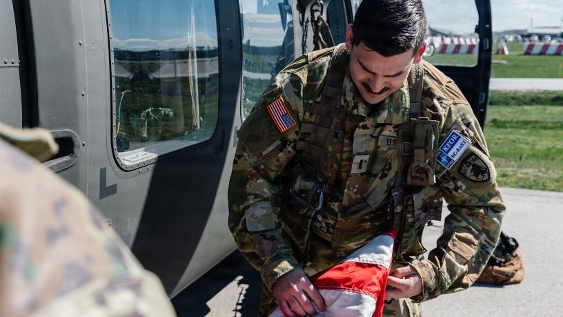 Colorado Army National Guard 1st Lt. Kellen Jansen, assistant operations officer with Headquarters and Headquarters Company, 2nd Battalion, 135th Aviation Regiment (General Support Aviation Battalion), assigned to Kosovo Force (KFOR) Regional Command-East, folds a U.S. flag at Camp Bondsteel, Kosovo, April 9, 2026.