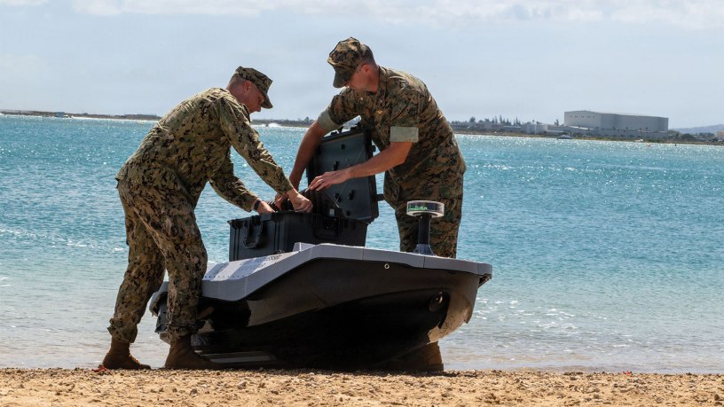 U.S. Marine Corps. Lt. Col. Michael Radigan and Lt. Evan Humphrey, a student at the Naval Postgraduate School, load cargo onto a digitally crewed surface vessel at the Honolulu Harbor Public Boat Ramp during Exercise Rim of the Pacific 2026 in Honolulu, Hawaii, July 7, 2026.